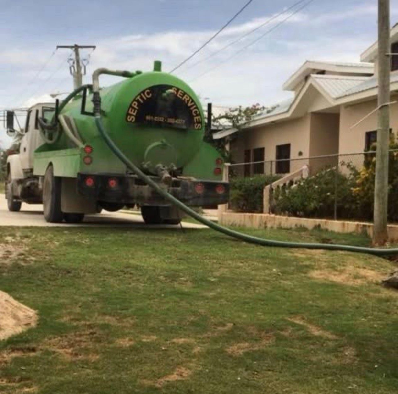 Sutherland Septic tank truck with hose running to a home